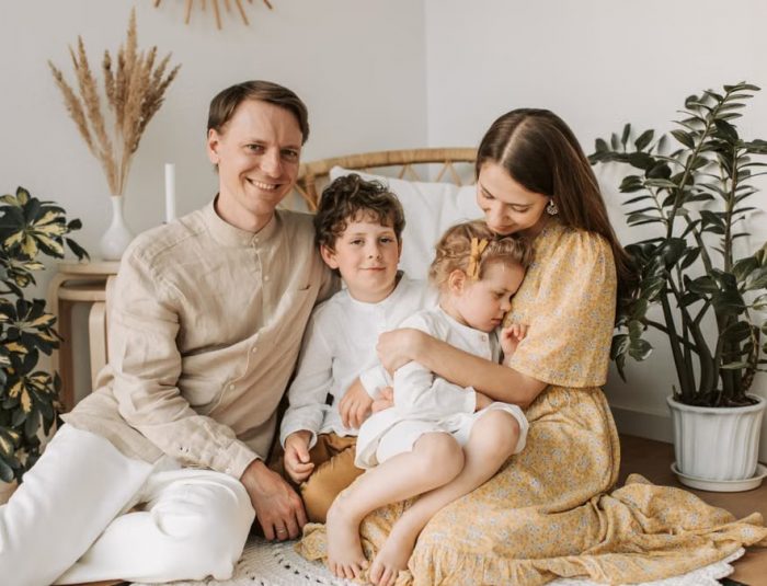 Happy family of four enjoying quality time together in a cozy, plant-filled room.
